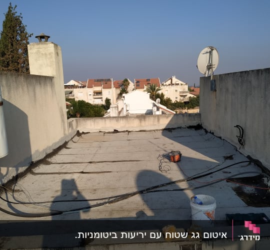 גג עם חומרים וכלים לאיטום, כולל דלי וכפפות